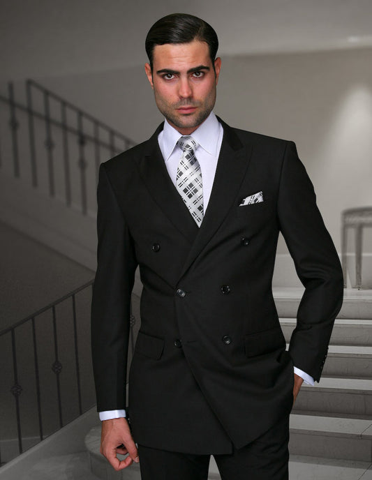 A man wearing the STATEMENT CLOTHING | SD-100-BLACK, a black tailored fit, double-breasted suit from Statement Clothing, stands in front of a staircase, accessorized with a patterned tie and pocket square.