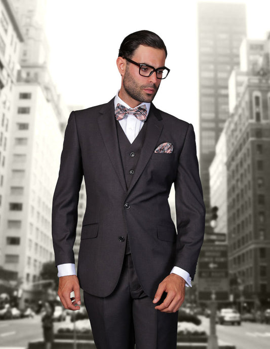 A man wearing the STATEMENT CLOTHING | STZV-100-H.CHARCOAL by Statement Clothing, showcasing a tailored fit with flat front pants, stands in front of a blurred urban background.