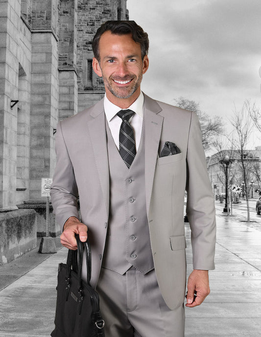 A man dressed in a STATEMENT CLOTHING | STZV-100-PLATINUM, tailored to perfection from luxurious Super 150's fabric, clutches a black bag while standing on an urban sidewalk. The scene is set against a grayscale image of a busy city street.