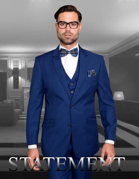 A man dressed in a sapphire blue suit from the STATEMENT CLOTHING | STZV-100-SAPPHIRE collection, complete with a bow tie, is posing inside a modern interior to highlight the sophistication of tailored fit designs. The product name "STATEMENT" is prominently displayed at the bottom, embodying the essence of refined style by Statement Clothing.