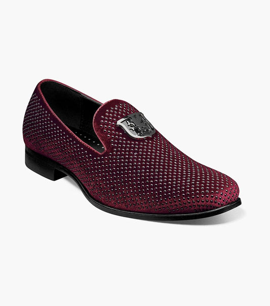 The Stacy Adams SWAGGER Studded Slip On in Burgundy, product number 25228-601, boasts a luxurious maroon velvet design with perforations and a silver emblem on the front. Its memory foam insole ensures superior comfort.