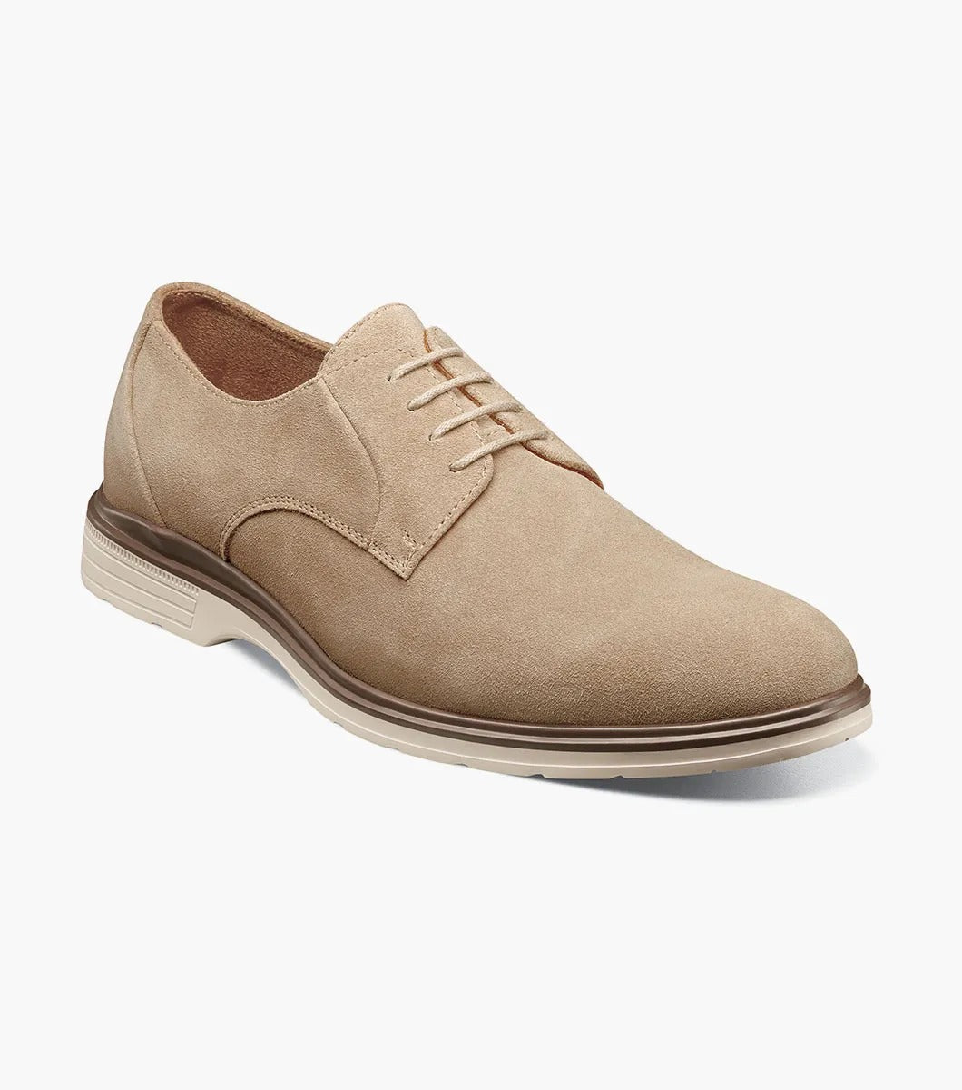 The Stacy Adams TAYSON Plain Toe Lace Up in sandstone is an Oxford shoe made from tan suede. It features anatomical arch support and laces, complemented by a light brown sole. The shoe is displayed against a plain white background.