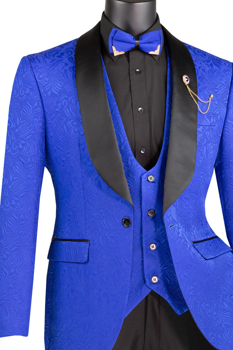 A mannequin features the Vinci Slim Fit 3 Piece Single Button Jacquard Fabric Tuxedo (Royal) TVSJ-1 by Vinci Suits, highlighted by a royal blue patterned suit with a matching vest and blazer. It's paired with a black shirt and pants, accentuated with a blue bow tie and gold chain on the lapel.