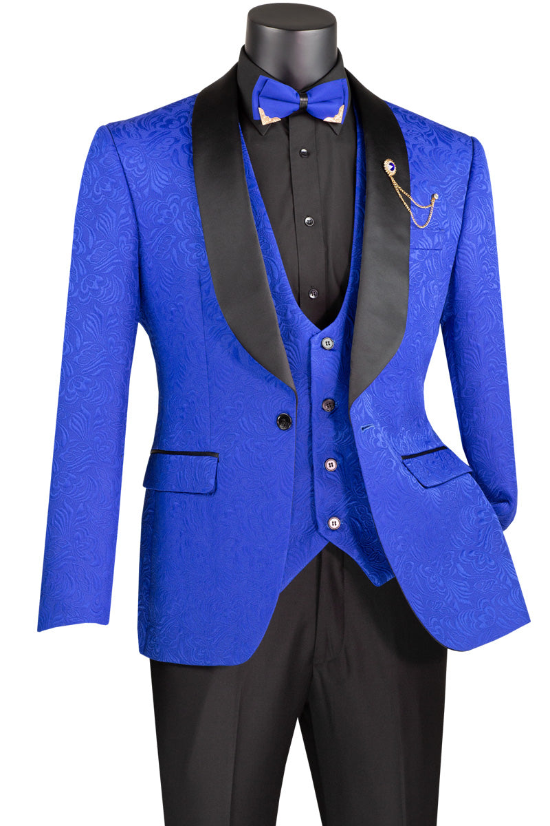 A mannequin features the Vinci Slim Fit 3 Piece Single Button Jacquard Fabric Tuxedo (Royal) TVSJ-1 by Vinci Suits, highlighted by a royal blue patterned suit with a matching vest and blazer. It's paired with a black shirt and pants, accentuated with a blue bow tie and gold chain on the lapel.