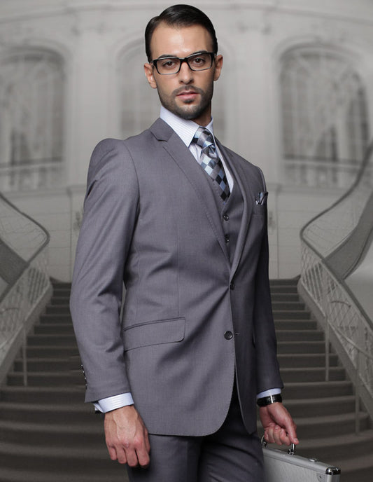 A man in a charcoal Statement Clothing TZ-100 suit and glasses stands on a staircase, holding a briefcase.