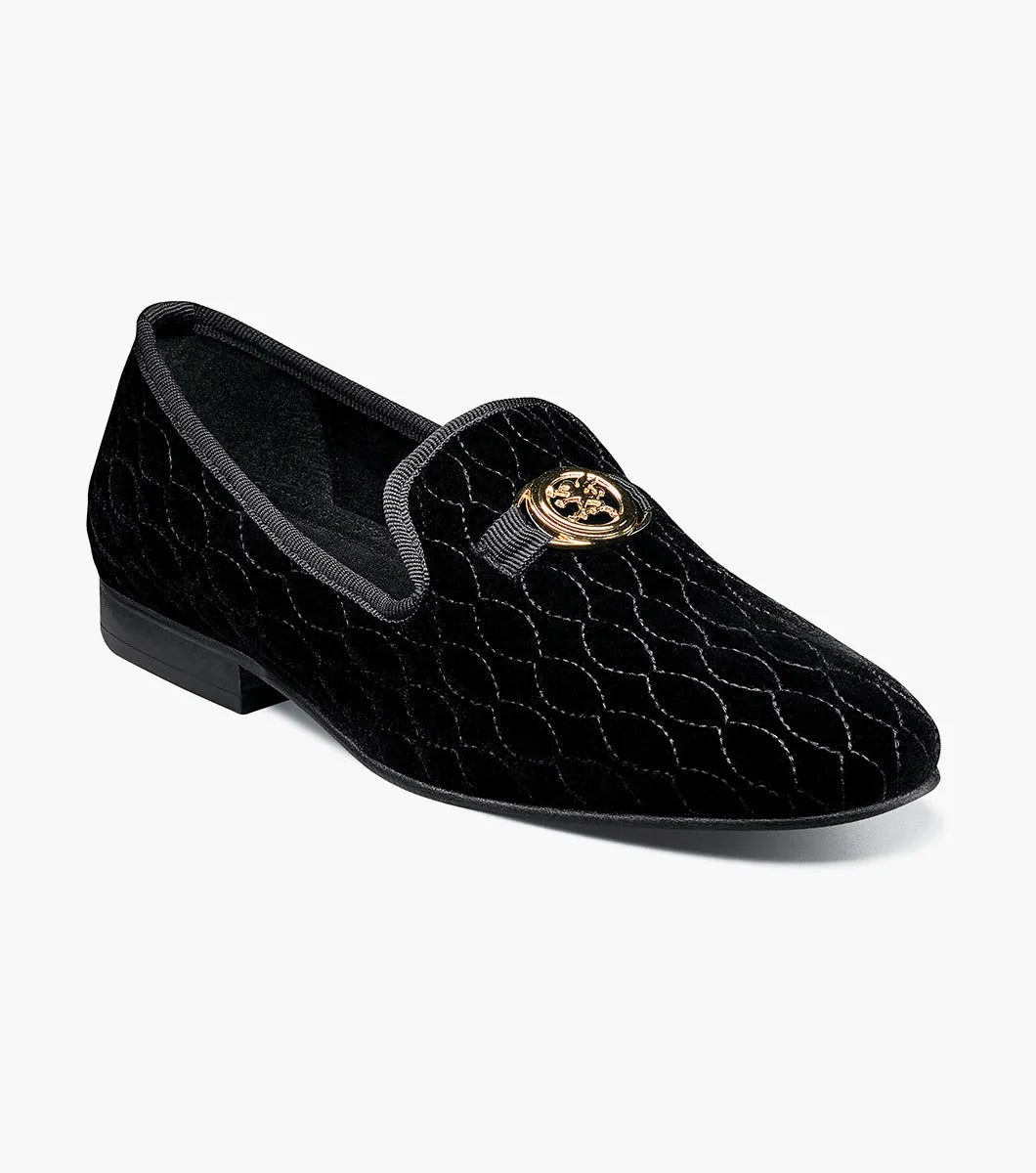 The Stacy Adams VALET Slip On Bit Loafer in Black (25166-001) showcases a black velvet design with a quilted pattern and gold emblem on top, enhanced by a genuine leather sole and cushioned with a Memory Foam insole for superior comfort.