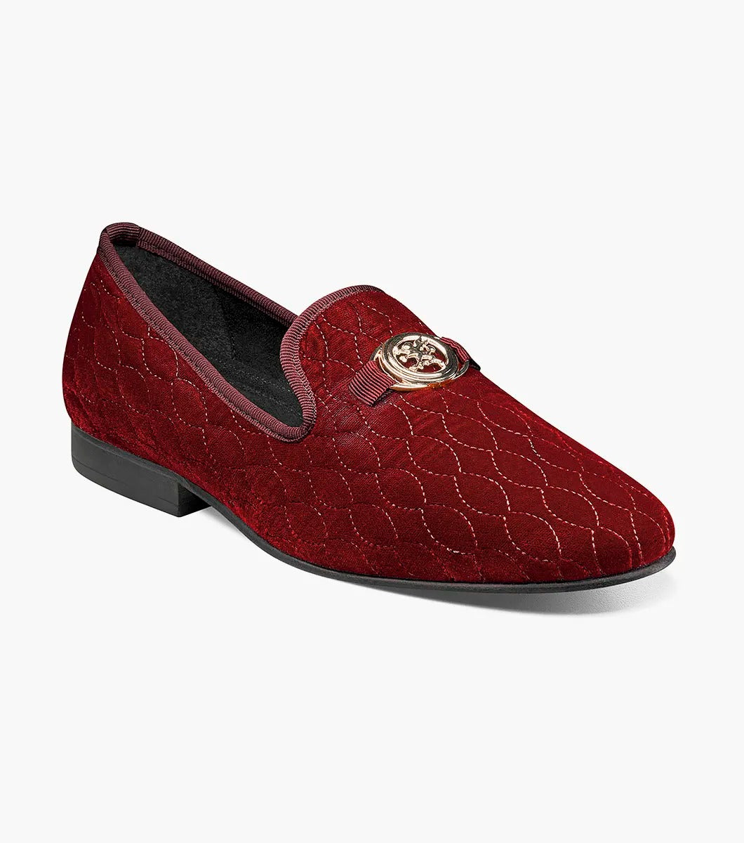 Introducing the Stacy Adams VALET Slip-On Bit Loafer in Burgundy (Product Code: 25166-601), this stylish footwear features a red velvet quilted pattern and is adorned with a gold emblem on the front. Crafted by STACY ADAMS, it boasts a genuine leather sole and incorporates a memory foam insole for enhanced comfort.