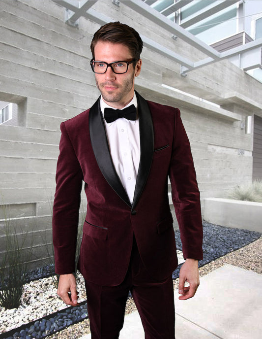 A man in a Statement Clothing VL-100-BURGUNDY tuxedo and glasses stands in front of a modern concrete building.