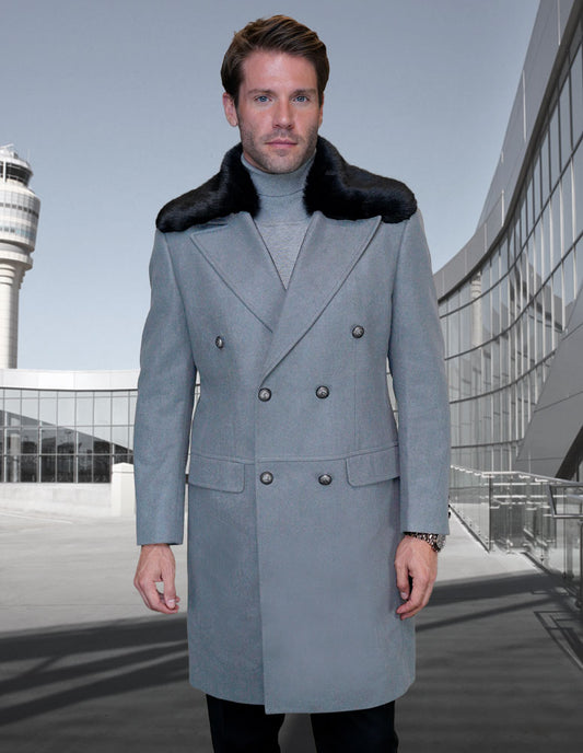 A man wearing the STATEMENT CLOTHING | WJ-102-GRAY, a gray double-breasted wool jacket with a removable fur collar from Statement Clothing, stands outdoors near a modern building and tower.