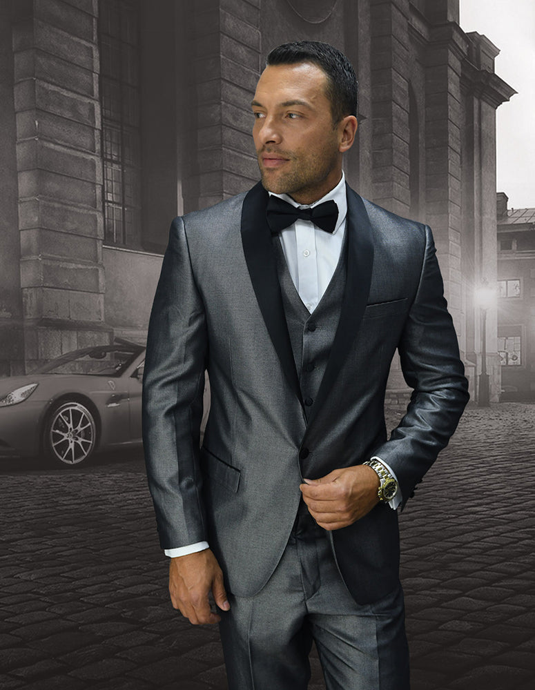 Dressed in the Wynn-Grey suit with flat front pants and a tailored fit from Statement Clothing, a man exudes confidence as he stands before a vintage car and an old building, finishing the ensemble with a striking bow tie.