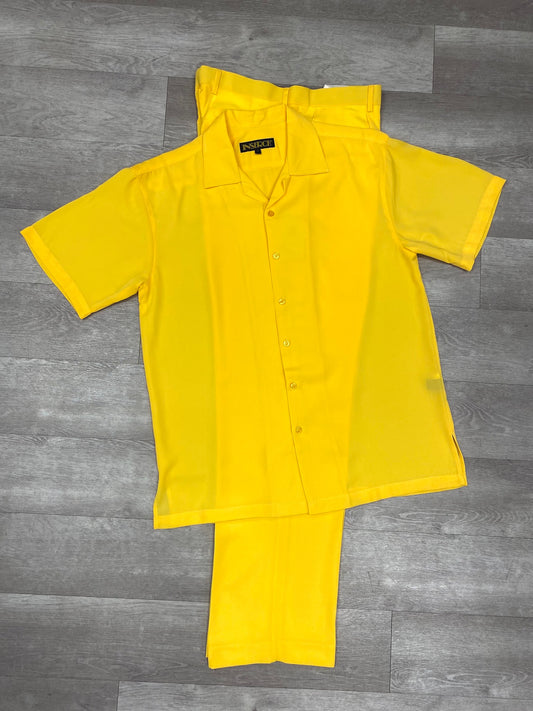 Introducing the Inserch 2pc 9356 Yellow, a vibrant ensemble by Inserch. This set includes a bright yellow short-sleeve button-up shirt paired with matching pants, elegantly displayed on a gray wooden floor.