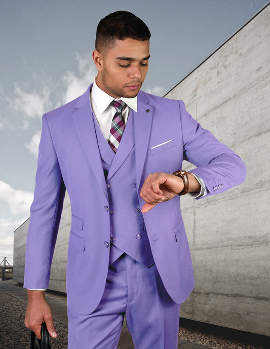 A man wearing the ZARGALA-LAVENDER Italian wool suit from Statement Clothing checks his watch while standing outdoors in front of a concrete structure.