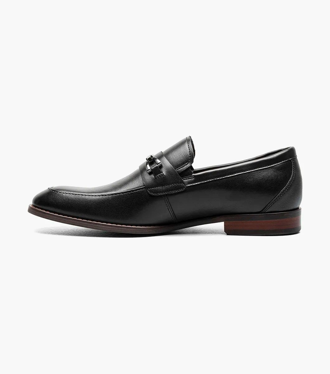 The Stacy Adams KAYLOR Moc Toe Bit Slip On in black (model 25572-001) is a sophisticated leather loafer from STACY ADAMS, highlighted by a sleek metal buckle, wooden heel, and premium leather upper. Perfectly set against a white background, it features the supportive RedZone footbed for exceptional comfort.