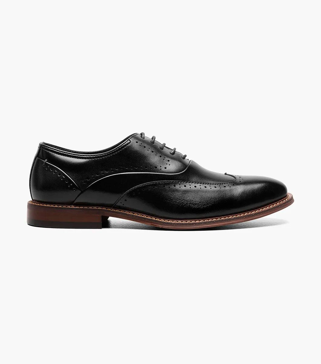 Introducing the Stacy Adams MACARTHUR Wingtip Oxford in Black Smooth (model 25489-005), a dress shoe crafted from burnished leather, featuring elegant decorative perforations and lace-up design, complete with a distinctive brown sole.