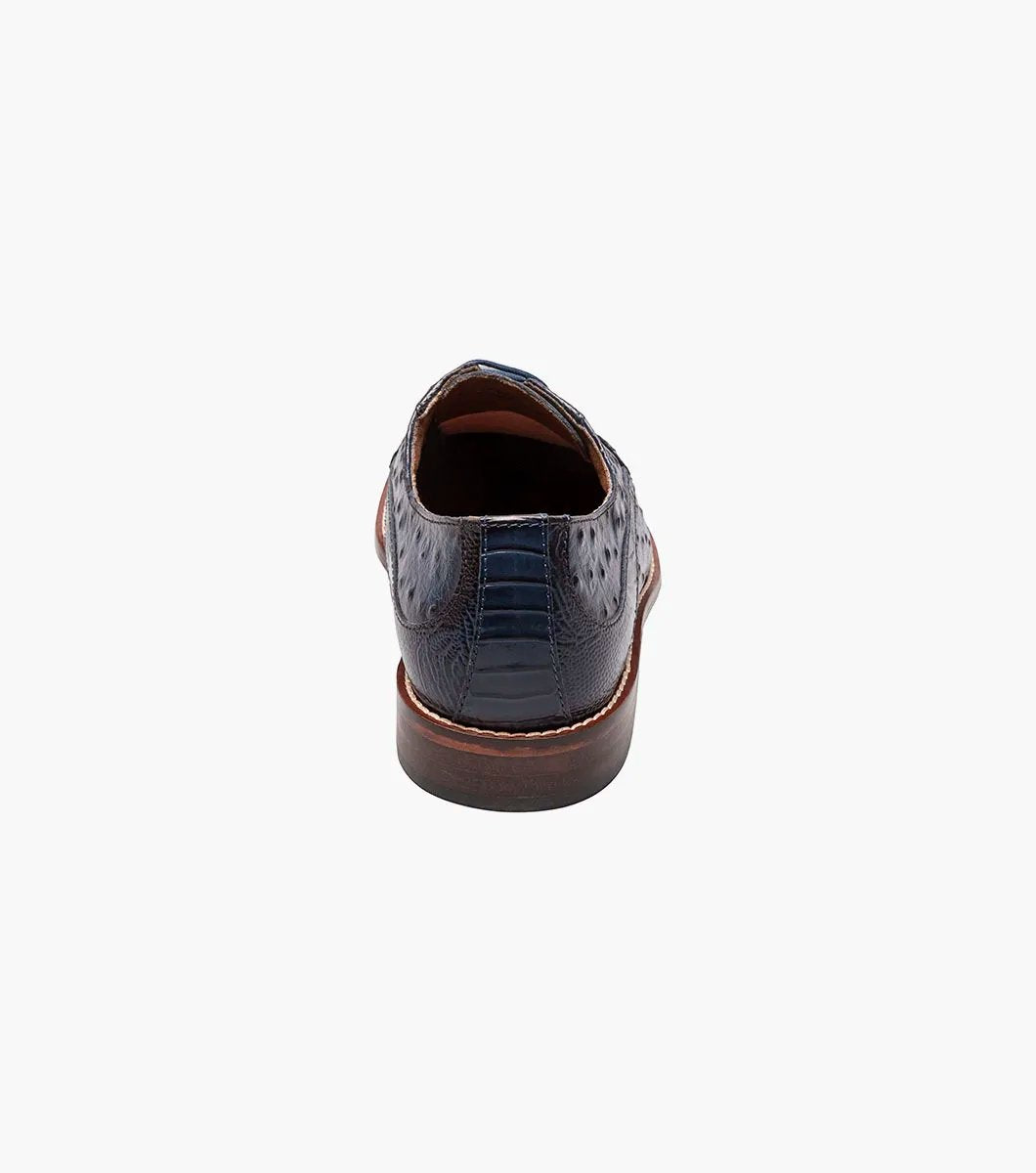 The Stacy Adams FANELLI Modified Wingtip Oxford in blue, product number 25536-400, is an elegant dress shoe made from luxurious ostrich leather. It features a textured pattern and a brown sole, shown here from an angled view.