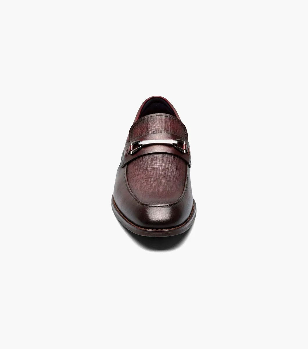 The Stacy Adams KAYLOR Moc Toe Bit Slip On in Burgundy, product number 25572-601, features a metal buckle detail, leather upper, low heel, and dark sole set against a plain white background.