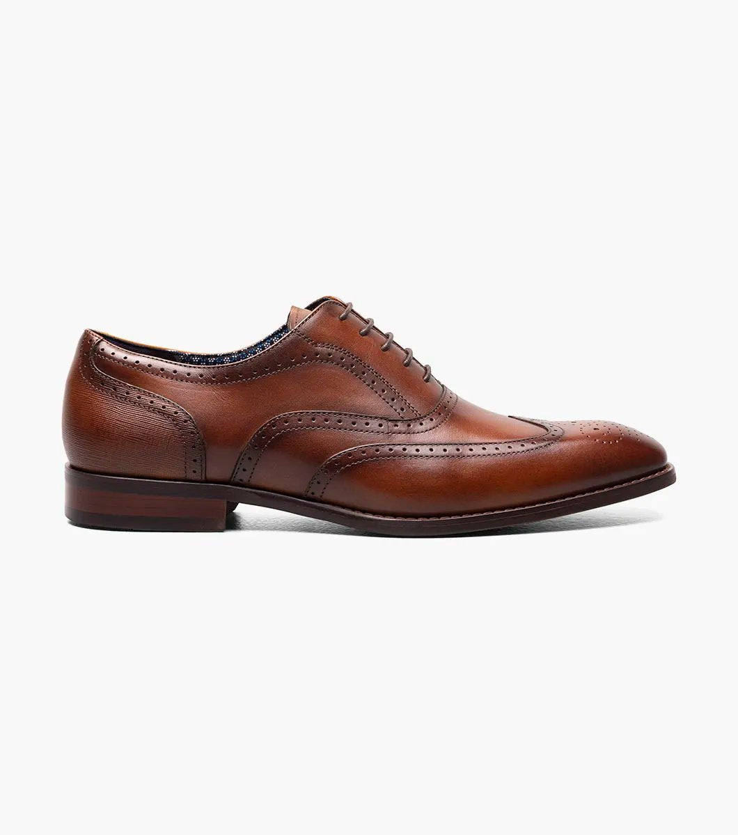 The Stacy Adams KAINE Wingtip Oxford in Cognac, model number 25569-221, from STACY ADAMS, is showcased against a white background, highlighting its intricate stitching and decorative perforations.