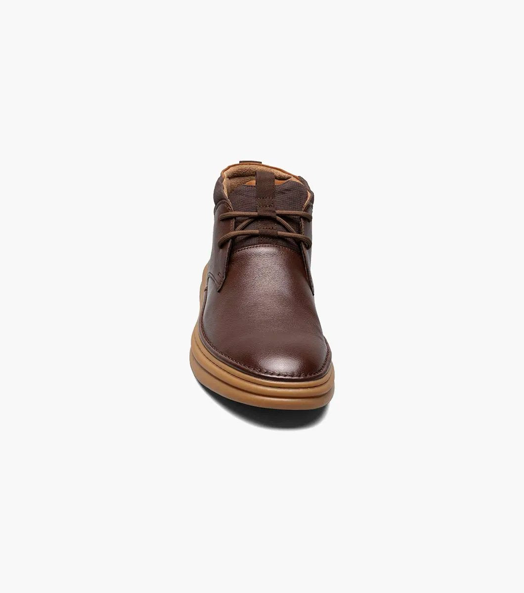 The Stacy Adams DELSON Plain Toe Chukka Boot in Chocolate, style number 25556-202, features a brown leather design with a rounded toe, lace-up front, and a cushioned brown sole with anatomical arch support, all presented against a white background.