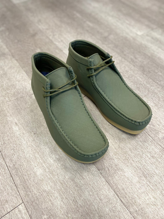 A pair of stylish olive-green Amali Jason Chukka Boots from Unique Design Menswear, featuring tan soles, sits elegantly on a light wooden floor.