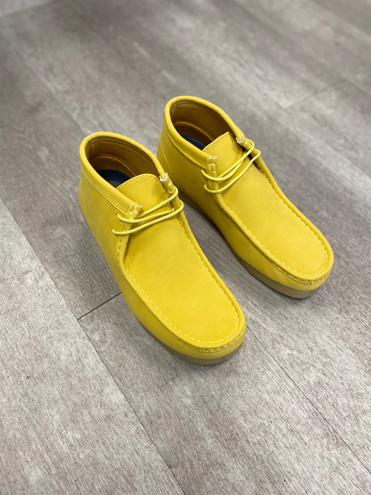 A pair of Amali Jason Chukka Boots in mustard from Unique Design Menswear, featuring laces and resting on a light wooden floor, exudes a stylish aura.