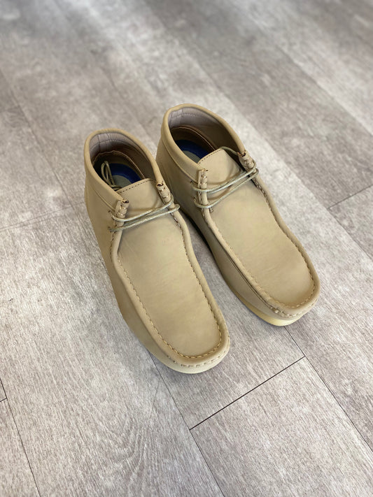 A pair of elegant Amali Jason Chukka Boots in tan leather from Unique Design Menswear, complete with laces, rests stylishly on a wooden floor.