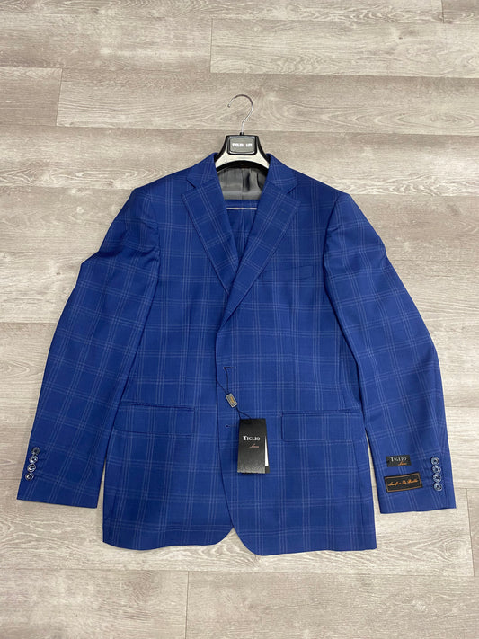 A blue windowpane suit jacket in pure wool with buttoned cuffs is displayed on a wooden floor, showcasing a Tiglio Luxe brand tag on its front and sleeve.