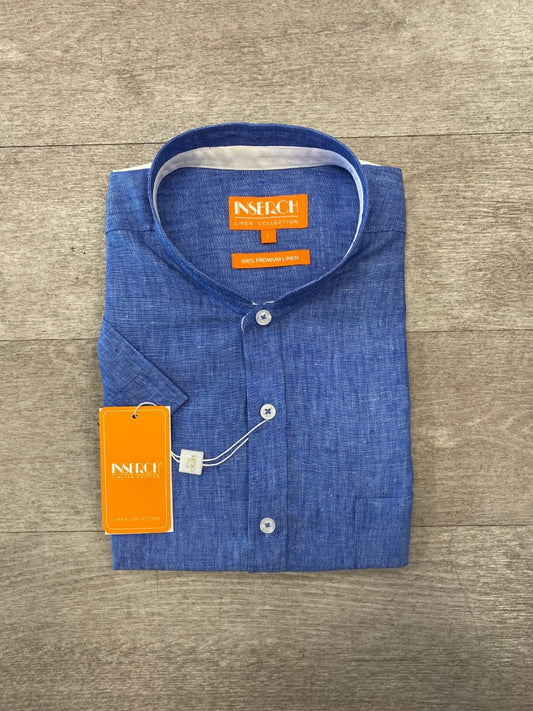 A folded Premium Linen Banded Collar Short Sleeve Shirt in blue from Inserch, showcasing a white interior collar and orange tags attached, is placed on a wooden surface.